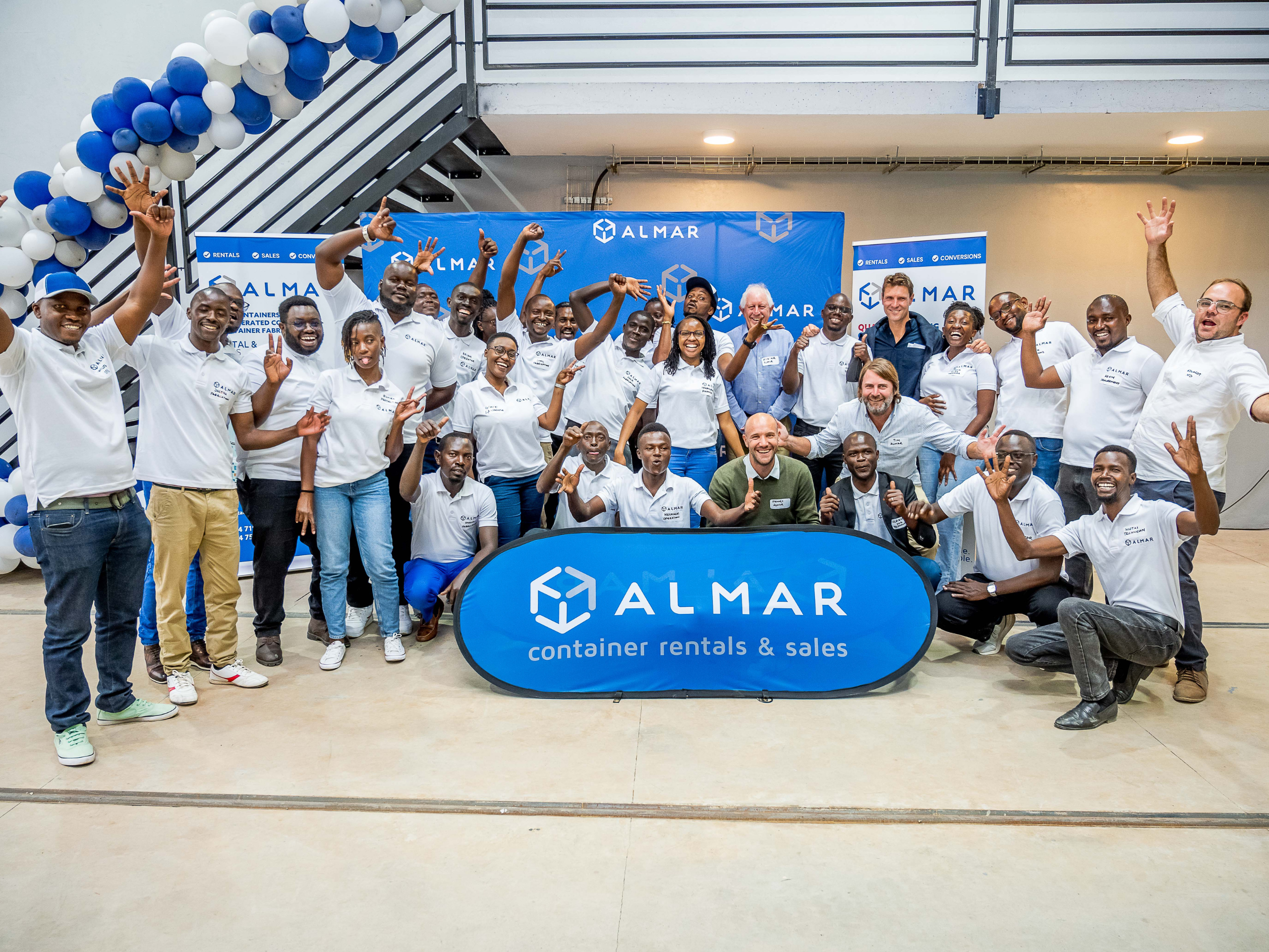 Almar Kenya staff in group photo in happy and funny shoot with Almar Banners and Blue and white balloons