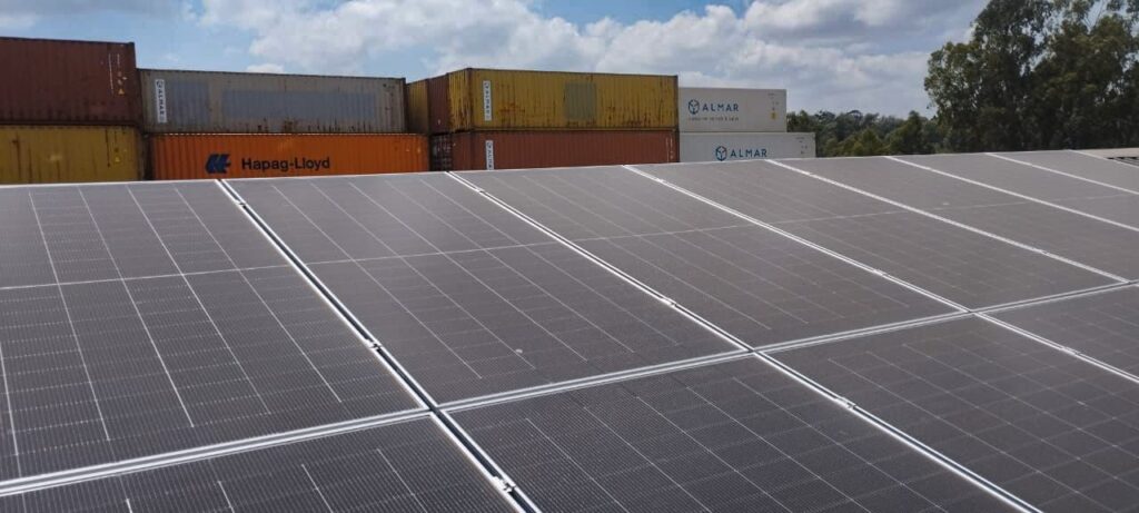 Alt Text: Rooftop solar panels at Almar Kenya's fabrication facility with branded Almar containers in the background.